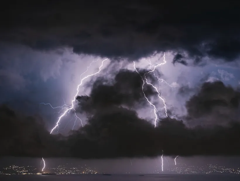 Gewitter über einer Ortschaft, Symbol für Blitzschutz