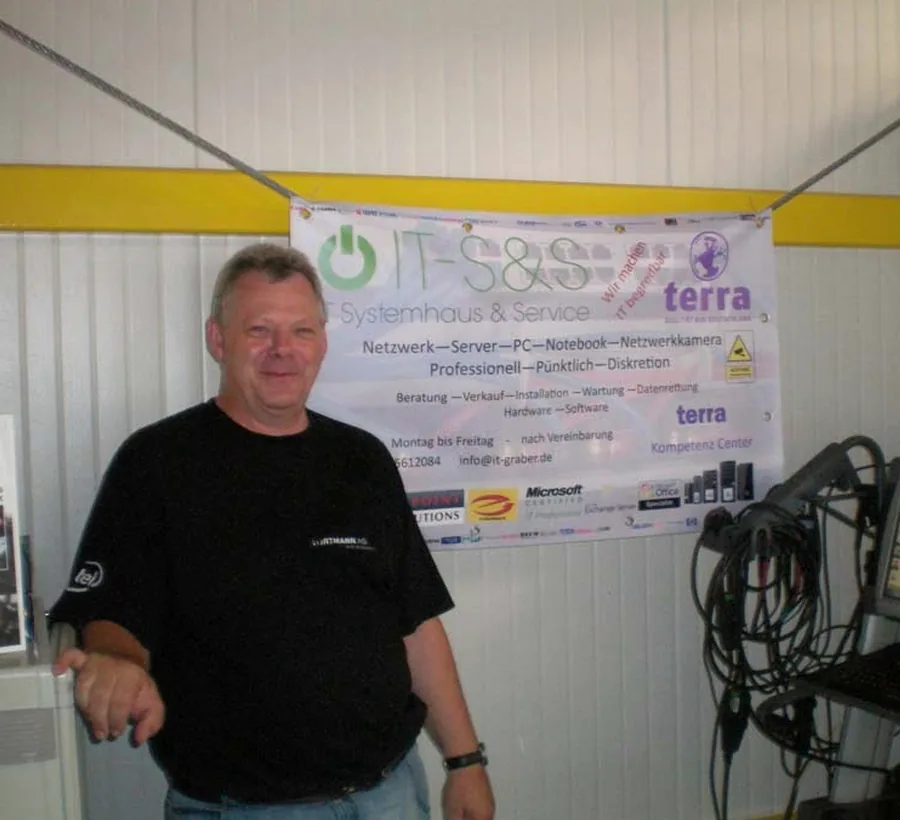 Detlef Graber, Inhaber von IT SundS, vor dem Firmenbanner in der Werkstatt